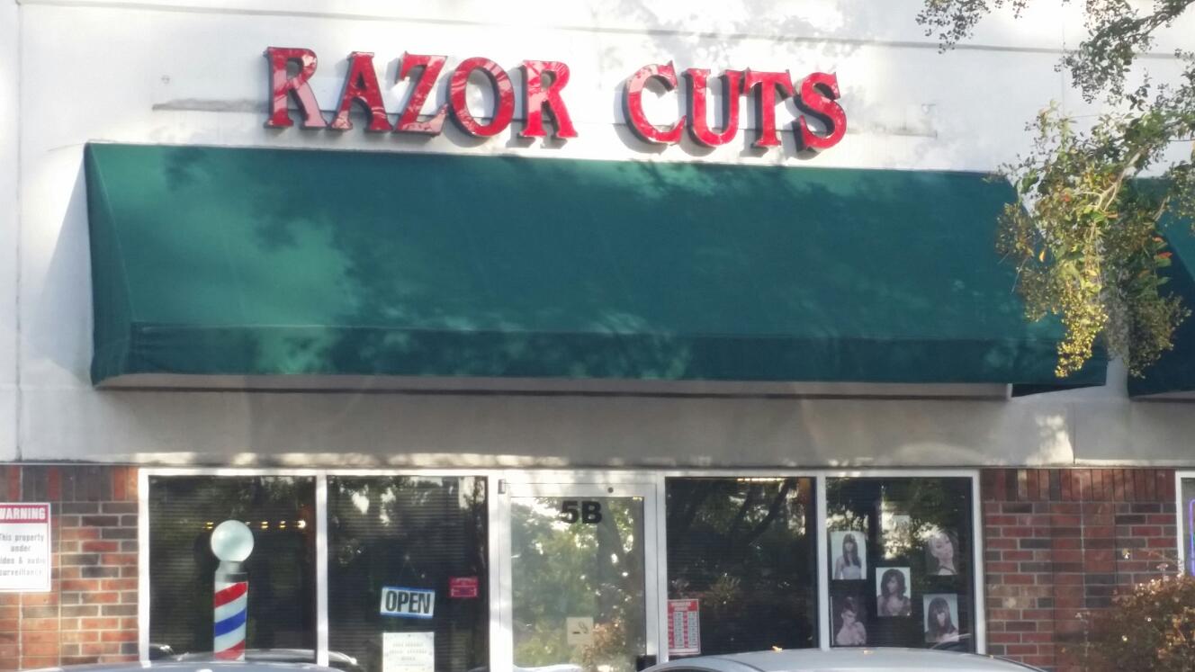 Razor Cuts storefront with its red lettering, green awning and barber pole