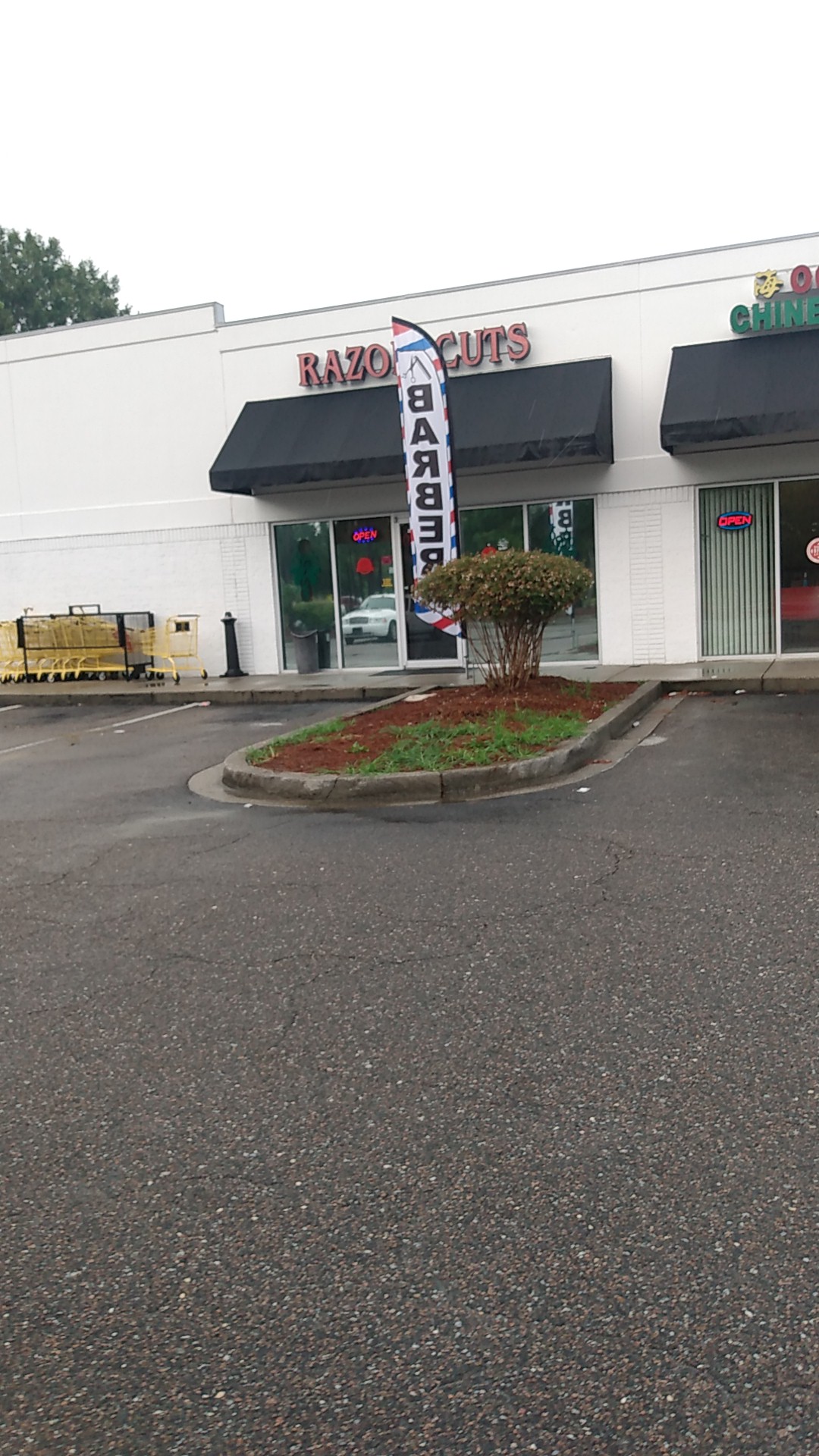 The Razor Cuts storefront with the barber flag out front
